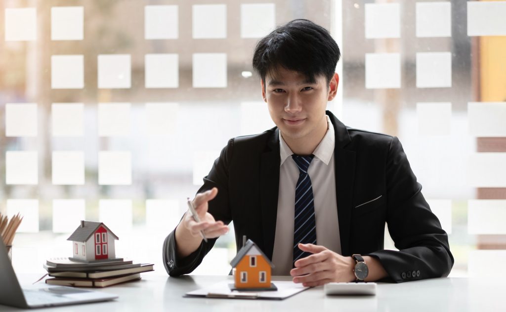Miniature house in the hands of an Asian bussinessman real estate agent home loan working at the